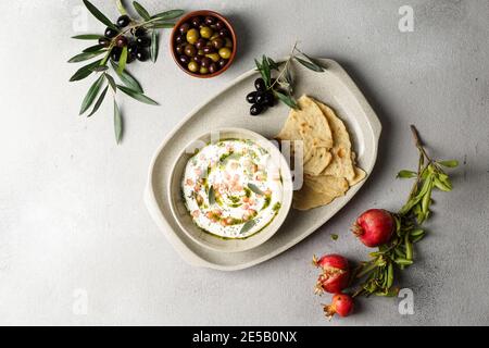 iranisches oder arabisches Gericht, Joghurt labneh Ziegen Milchdip mit Taftbrot und Granatapfel Stockfoto