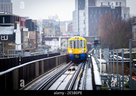 Ein Overground Zug nähert sich Haggerston Station an einem kalten verschneiten Tag. Stockfoto