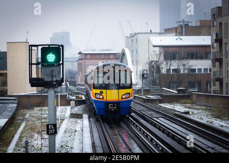 Ein Overground Zug nähert sich Haggerston Station an einem kalten verschneiten Tag. Stockfoto