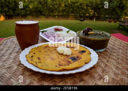 Seitenansicht von Makki di roti und Sarson da saag, Senfblätter Curry und ungesäuertes Maismehlbrot serviert in einer authentischen Art Dorf Stil im Freien Stockfoto