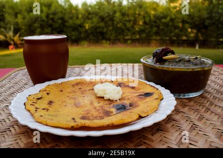 Seitenansicht von Makki di roti und Sarson da saag, Senfblätter Curry und ungesäuertes Maismehlbrot auf authentische Weise im Freien serviert. Punjabi trad Stockfoto