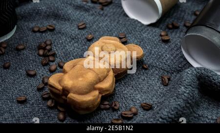 Hintergrund von Kaffee und Gebäck Teddybär, aromatischer Kaffee mit Gebäck, Kaffeebohnen auf Seidenstoff, Cappuccino in einer gemütlichen Atmosphäre Stockfoto