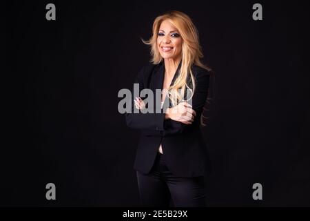 Blonde Frau, Geschäftsfrau, mittleren Alters, europäisch-Portugiesisch, posiert mit positiven Emotionen auf schwarzem Hintergrund. Stockfoto
