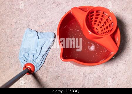 Standpunkt der Mopp Reinigung Linoleum Boden in der Nähe rot Eimer mit Wasser zu Hause Stockfoto