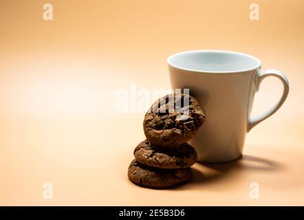 Nahaufnahme eines weißen Krug Milch und eines Haufen Dunkler Schokoladenkekse Stockfoto