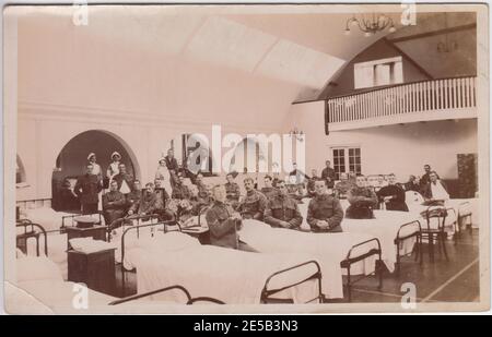 Station in einem Militärkrankenhaus des Ersten Weltkriegs in oder um Brockenhurst, New Forest. Das Foto zeigt Reihen von Betten mit Soldaten, die neben ihnen sitzen. Krankenschwestern und einige Soldaten stehen unter Bögen auf der Rückseite des Raumes. Stockfoto