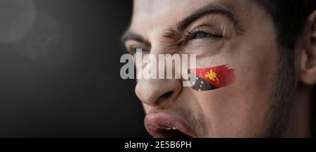 Ein schreiender Mann mit dem Bild der Papua-Neueinung Guinea Nationalflagge auf seinem Gesicht Stockfoto