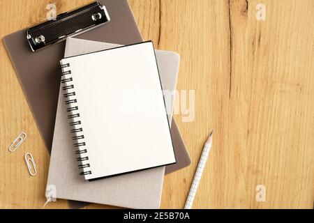 Stapel von Zwischenablage, Notizbuch, Notizblock und Bürobedarf auf Holztisch. Draufsicht, flach liegend. Stockfoto