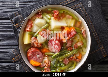 Luxemburgische Suppe aus grünen Bohnen, Kartoffeln, Lauch, Karotten mit der Zugabe von Würstchen und Speck Nahaufnahme in einem Teller auf dem Tisch. Horizontal oben V Stockfoto