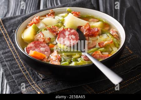 Luxemburgische Suppe aus grünen Bohnen, Kartoffeln, Lauch, Karotten mit der Zugabe von Würstchen und Speck Nahaufnahme in einem Teller auf dem Tisch. Horizontal Stockfoto