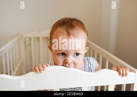 Baby Mädchen steht in ihrer Krippe zu Hause Stockfoto