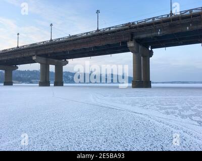 Paton Brücke über gefrorenen Dnipro Fluss. Pechersk Lavra im Hintergrund. Kiew, Ukraine Stockfoto