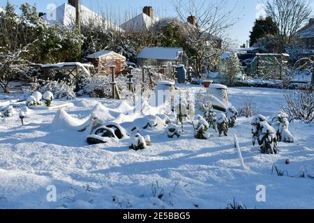 Eine schneebedeckte Gartenanlage mit blauem Himmel und Dach Tops an einem sonnigen Wintertag Stockfoto