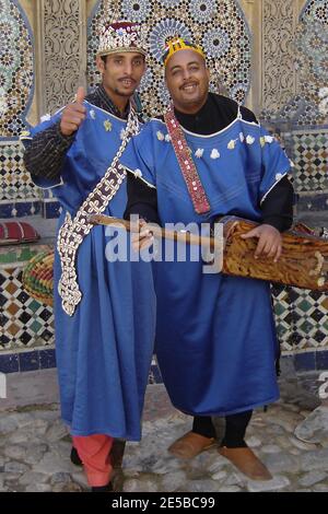 Straßenmusiker in Tanger, Marokko 2005 - der Mann auf der rechten Seite spielt eine gimbri (auch bekannt als sintir, guembri , gimbri, hejhouj oder hajhuj), eine Art Laute mit drei Saiten (gestimmt mit einer Stimmschlinge), die gezupft wird. Stockfoto