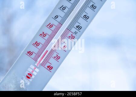 Das Thermometer liegt im Winter auf dem Schnee und zeigt eine niedrige ...