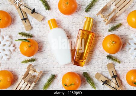 Winter Flat Lay mit Haarpflegeprodukten, Schneeflocken, Mandarinen, Schlitten und Skiern auf weißem Strickhintergrund. Stockfoto