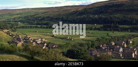 Weite Panoramablick auf das Dorf und Heuwiesen von Gunnerside, Swaledale, Yorkshire Dales National Park, in Abendlicht. Stockfoto