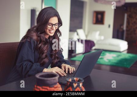 Intelligente junge kaukasische Frau, die ihre Aufgabe online und haben Spaß im Home Office Stockfoto