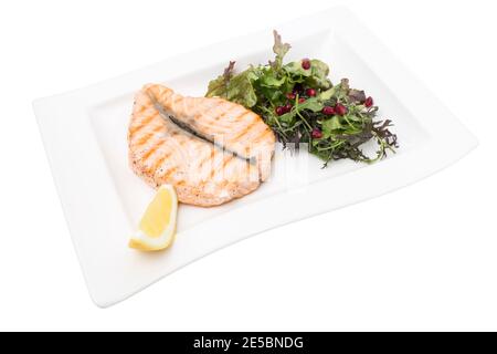 Steak vom gegrillten Lachs mit Gemüsesalat. Dieser ist in einem weißen Hintergrund isoliert. Nahaufnahme. Stockfoto