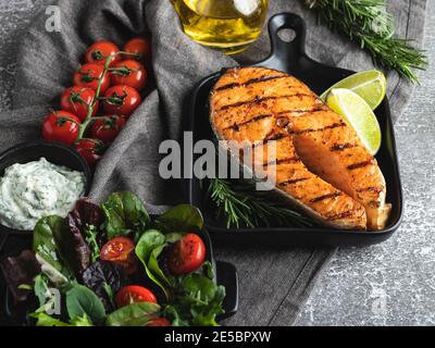 Gegrillter Steak Fisch Lachs, Forelle in einer Grillpfanne, Gewürze, frischer Salat, Tomaten, Stockfoto