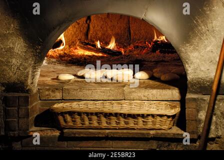 Traditionelles Holz gebackenes Brot, das in einen superheißen Backsteinofen gelegt wird. Stockfoto