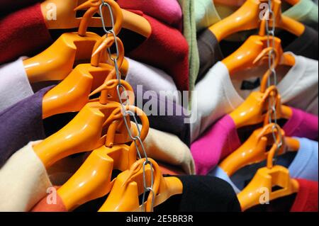 Bunte Strickjacken an orangefarbenen Kleiderbügeln Stockfoto