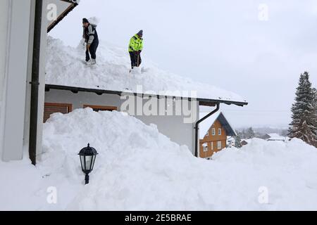 Zwei Männer schaufeln hohen schweren Schnee von einem Hausdach Stockfoto