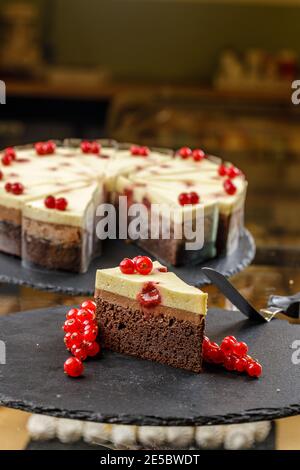 Nahaufnahme eines Stücks köstlicher Kuchen mit roter Johannisbeere und kitschiger Schlagsahne. Leckerer Käsekuchen Stockfoto