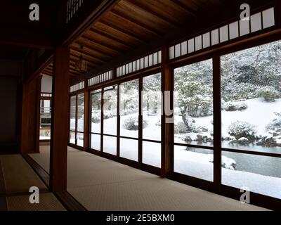 Japanischer Wintergarten mit Blick von einem traditionellen Zimmer im Inneren mit Panoramafenster Stockfoto