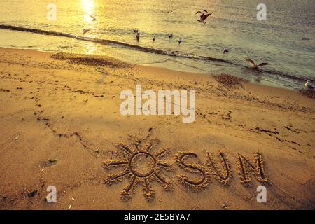 Das Wort SONNE auf dem Strand Sand bei Sonnenuntergang geschrieben Stockfoto