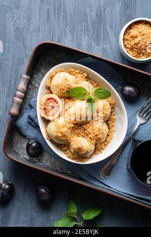 Frisch gekochte Pflaumenknödel garniert mit süßen gerösteten Paniermehl in einer Schüssel, serviert mit schwarzem Johannisbeersaft Stockfoto