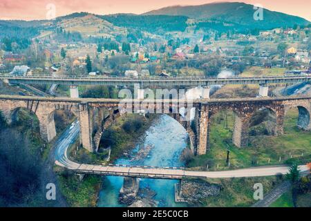 Panoramablick auf die Stadt Vorokhta im Bergtal. Drei Brücken über den Fluss Prut. Blick auf die Straßenbrücke und zwei Eisenbahnbrücken Stockfoto