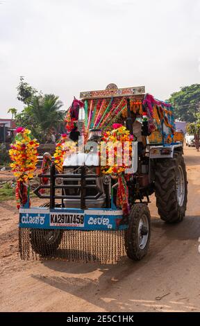 Nandakeshwar, Karnataka, Indien - 7. November 2013: Frontale Nahaufnahme des blauen Traktors auf Feldstraßensportarten mehrere Blumenleis für Diwali unter Silber sk Stockfoto