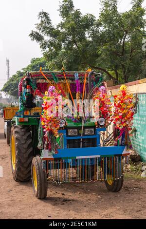 Nandakeshwar, Karnataka, Indien - 7. November 2013: Frontale Nahaufnahme des blauen Traktors auf Feldstraßensportarten multiple und übermäßige Blume Leis für Diwali U Stockfoto