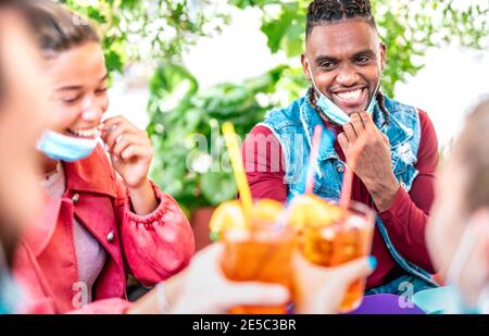 Freunde trinken an der Cocktailbar mit Gesichtsmasken - Neu Normales Freundschaftskonzept mit glücklichen Leuten, die Spaß zusammen toasten Getränke im Open-Air-Pub Stockfoto