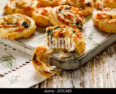 Blätterteig Vorspeisen Pinwheels gefüllt mit Lachs, Käse und Spinat auf Holzbrett Nahaufnahme Stockfoto