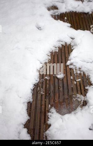Schmelzender Schnee auf Dielen Stockfoto
