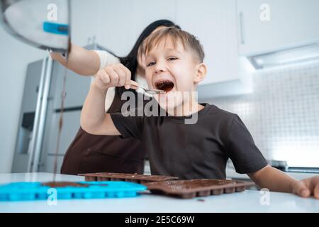 Glückliche Mutter und Kind Herstellung Schokolade Süßigkeiten und Spaß haben Zu Hause Küche Stockfoto