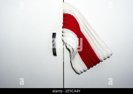 Strickschal weiß rot weiß ragt aus dem Schrank Türen schließen Stockfoto