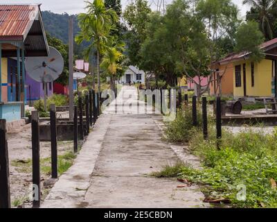 Kensi, Arguni, Indonesien - 01. Februar 2018: Bunte Holzhäuser in einem kleinen Dorf im indonesischen Tropenwald und Kirche am Ende der Stockfoto