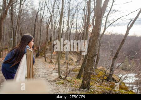 Ein Mädchen mit langen Haaren lehnt sich auf Zaun starrt aus Über einem bewaldeten Tal Stockfoto