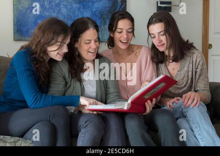 Eine Mutter und ihre drei Töchter lachen beim Betrachten Ein Fotoalbum Stockfoto