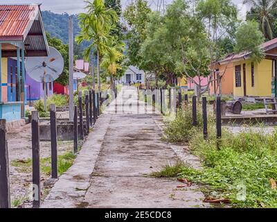 Kensi, Arguni, Indonesien - 01. Februar 2018: Bunte Holzhäuser in einem kleinen Dorf im indonesischen Tropenwald und Kirche am Ende der Stockfoto