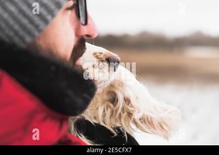 Die Nase des Hundes neben dem Gesicht eines männlichen Menschen im Freien. Aktiver Lebensstil, gute Zeit mit Haustieren im Winter, geringe Tiefenschärfe Stockfoto