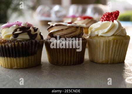 Nahaufnahme von Marmor-Cupcake mit Schokoladensauce, Butterscotch-Cupcake mit Sahnehäubchen und Vanille-Cupcake mit Buttercreme mit Fondant-Desserttopfern Stockfoto