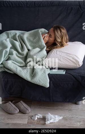 Kranke Frau zu Hause liegt im Bett leiden an Allergie, Grippe-Symptom, Fieber, Niesen in Papiergewebe Stockfoto