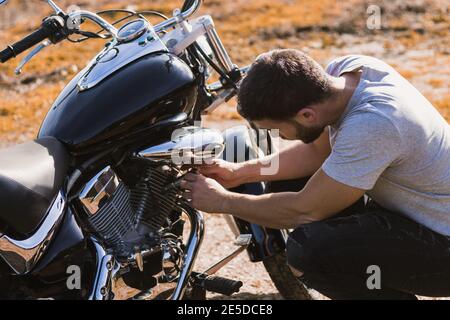 Crouching Biker besorgt über eine Motorrad-Panne Stockfoto