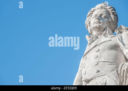 Warmer Sonnenuntergang über dem Mozart-Denkmal vor dem Palmenhaus, in der Nähe der Neuen Burg und der Hofburg, in der historischen Innenstadt von Wien, Österreich bei Sonnenschein Stockfoto