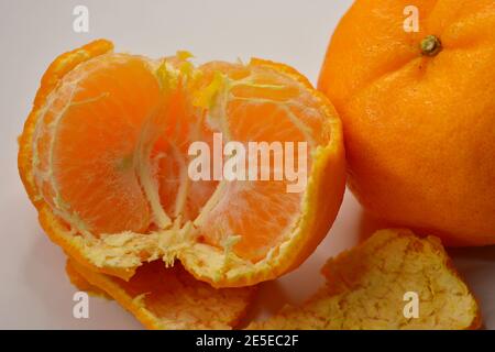 Die Hälfte einer geschälten Mandarinorange (Lukan Sorte) und Haut, vor weißem Hintergrund Stockfoto