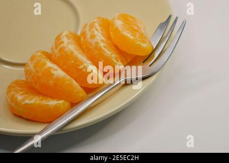 Scheiben geschälter Mandarinorangen (Lukan-Sorte) auf einem Servierteller, vor weißem Hintergrund Stockfoto